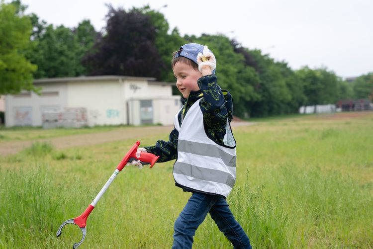 Kind, das Müll auf einer Wiese sammelt