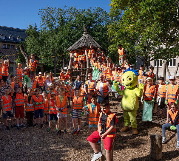 Kinder in Warnwesten mit Maskottchen Müllmo