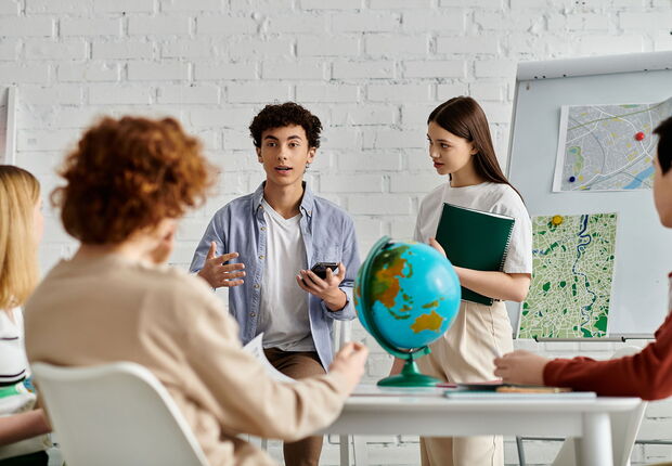 Jugendliche führen eine Diskussion und stehen um einen Tisch versammelt