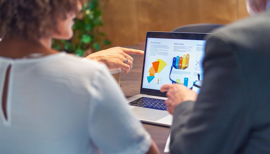 Zwei Personen schauen sich eine Grafik auf einem Laptop an