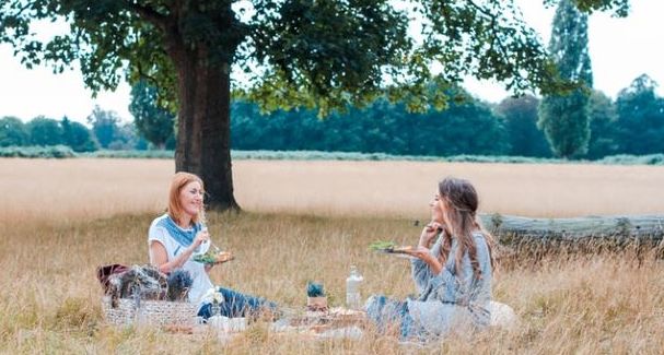 Zwei Frauen picknicken auf einer Wiese