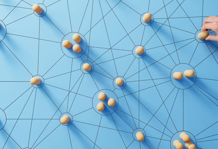 Darstellung eines Netzwerks von Menschen anhand von Holzfiguren auf blauem Grund 